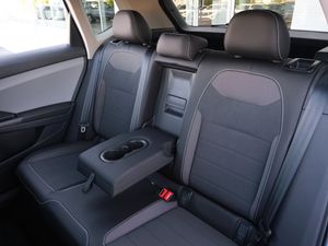 Rear seats of a modern car with black leather upholstery and center armrest.