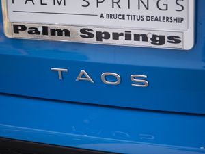 Palm Springs dealership badge and Taos nameplate on blue vehicle exterior.