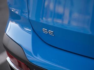 Close-up of SE badge on blue car exterior panel.