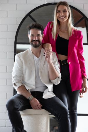 Professional studio portrait against white brick wall with modern round window frame.
