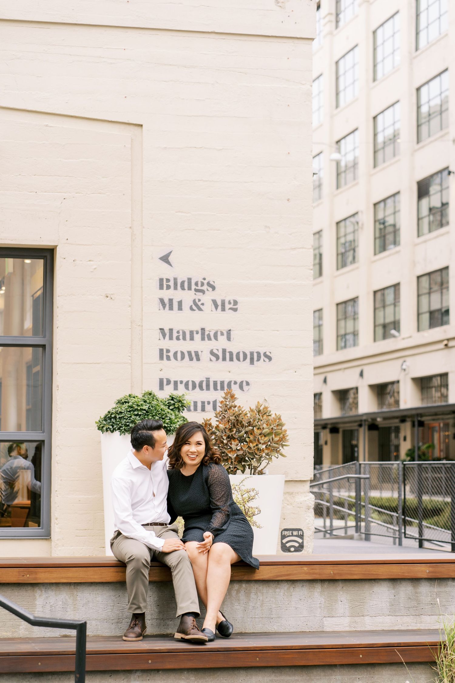 Couple sitting on bench outside urban storefront with vintage signage.