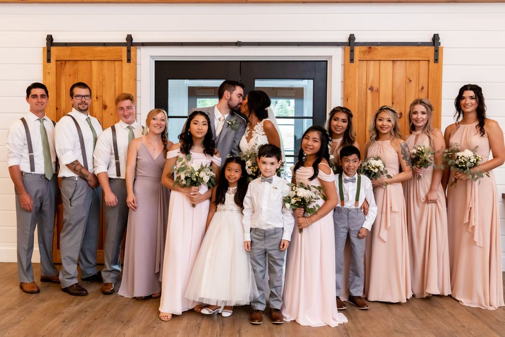 Wedding party portrait in rustic wooden venue with sliding barn doors.