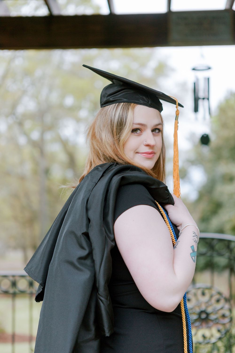 Young woman holds graduation gown over shoulder Augusta, GA