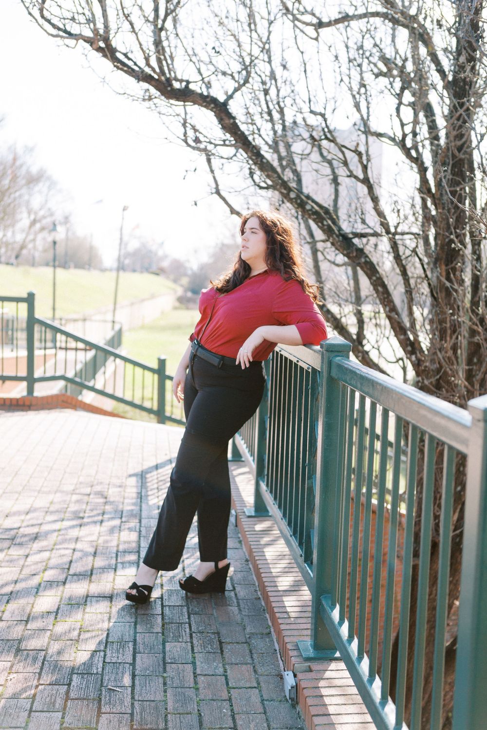 Young person in red and black leans against railing Augusta Riverwalk August, GA