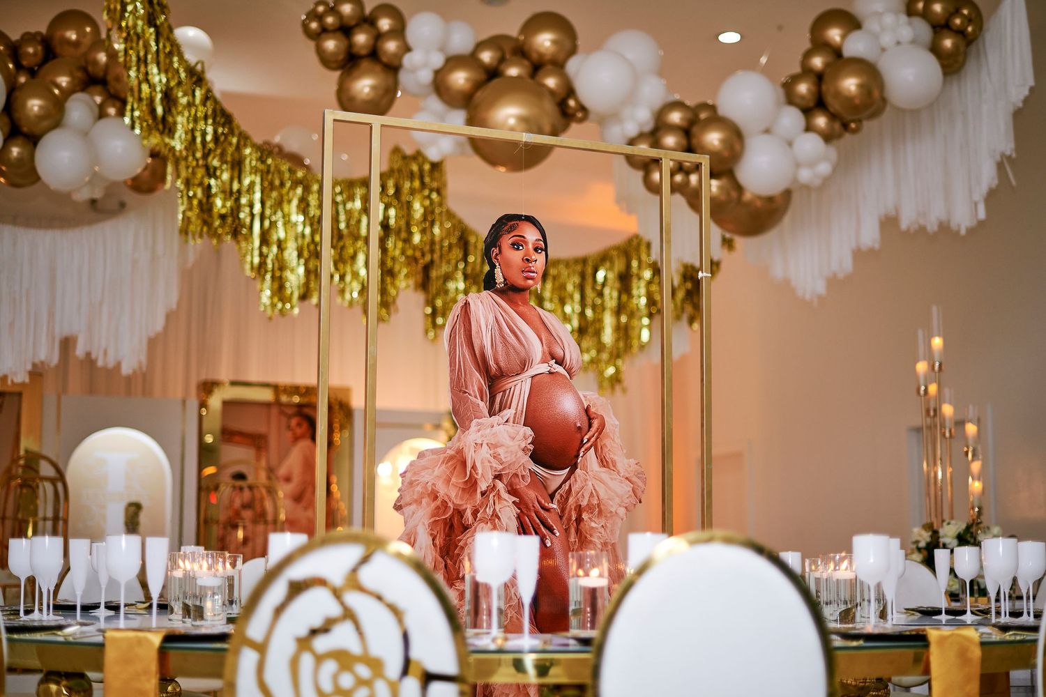 Elegant party decor with gold balloon clusters, glittering tinsel backdrops and chic white seating arrangements.