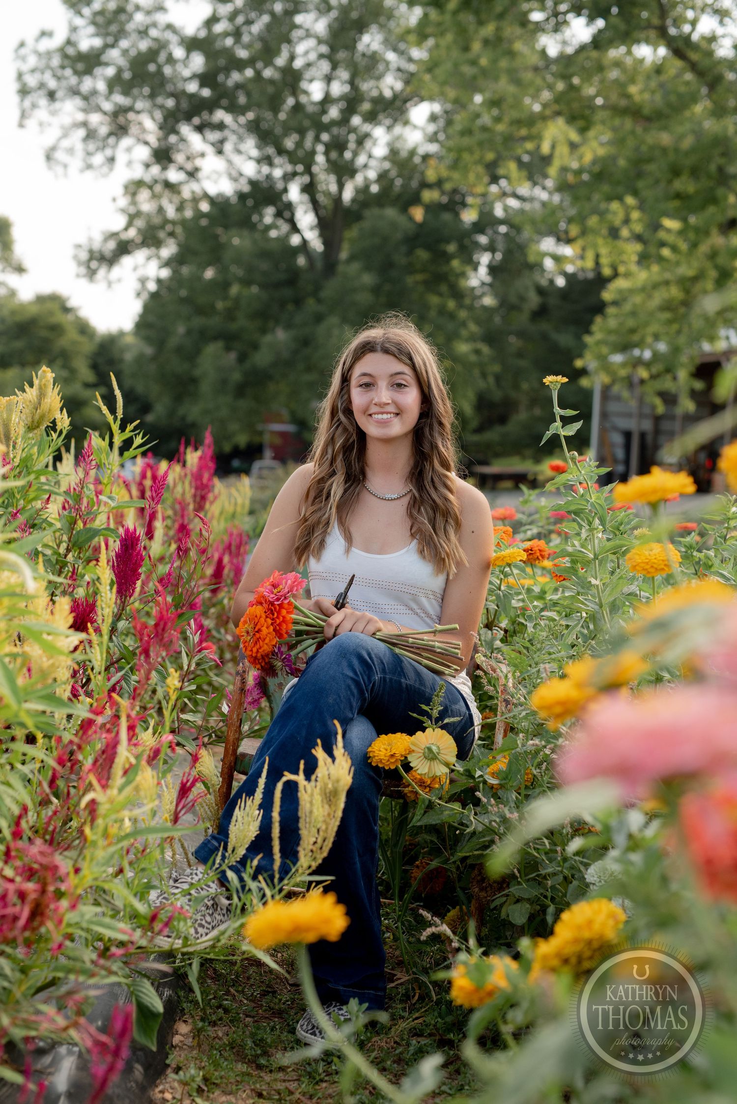 Person relaxing in colorful flower garden with pink celosia and yellow marigolds.