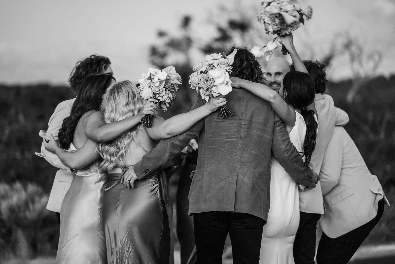 Wedding party celebrates with champagne toasts and laughter in black and white photograph.