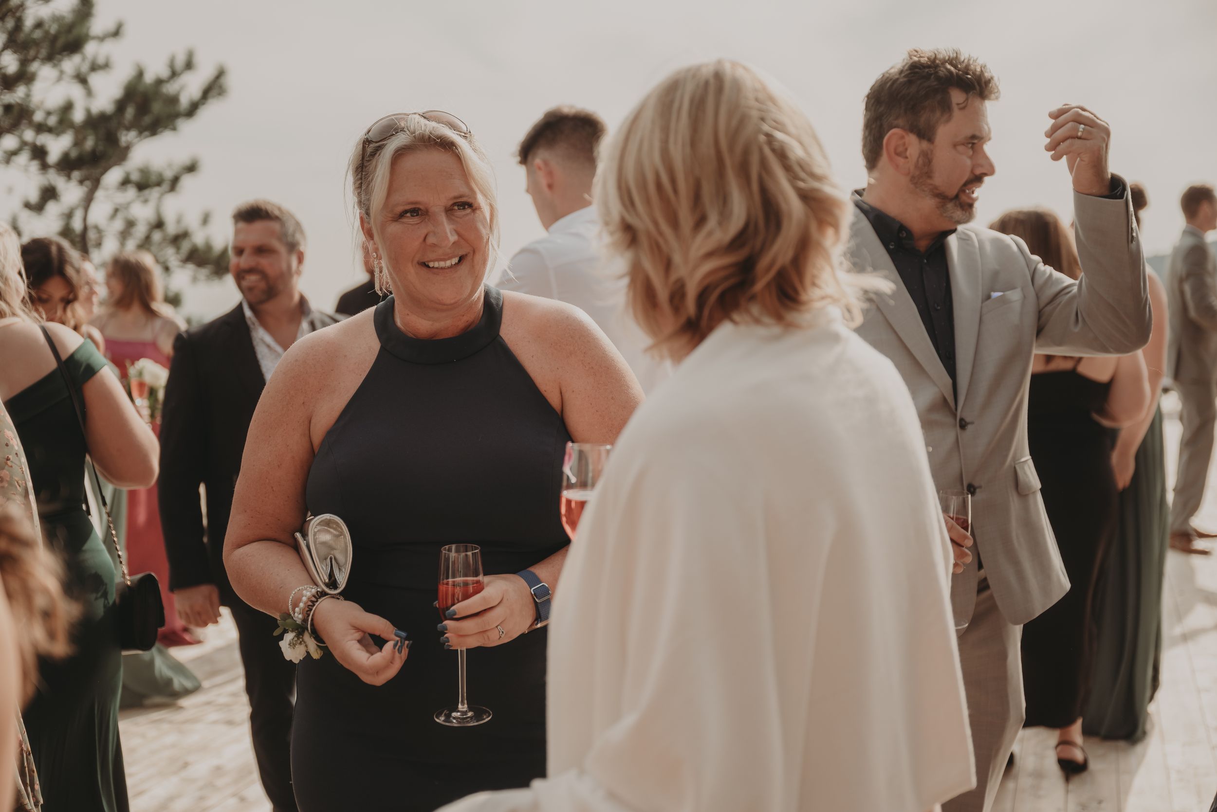 Guests mingling at an elegant outdoor party with champagne glasses.