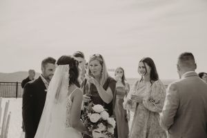 Black and white candid photo of wedding guests mingling during outdoor ceremony.