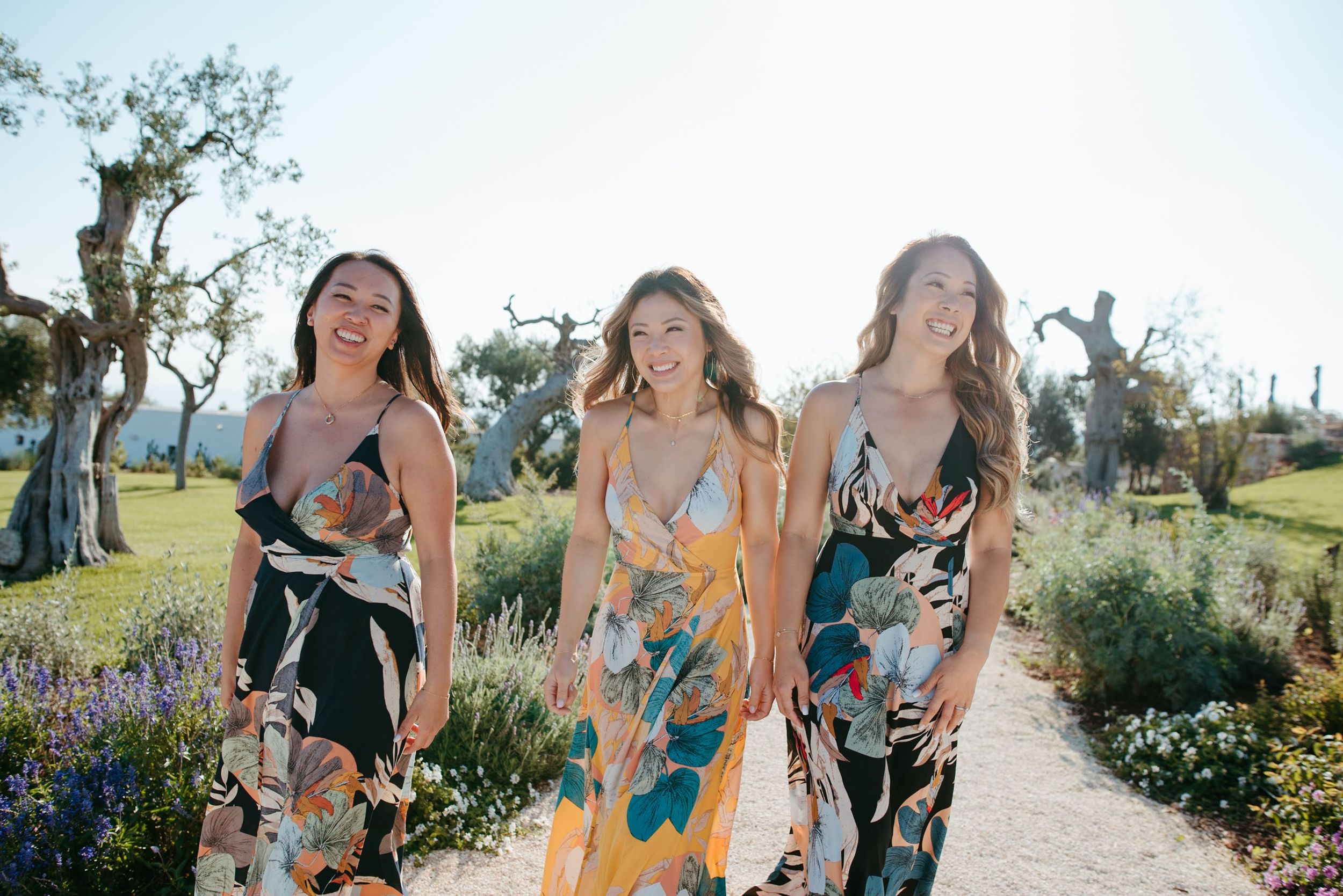 Friends laughing together in garden setting with blooming flowers.