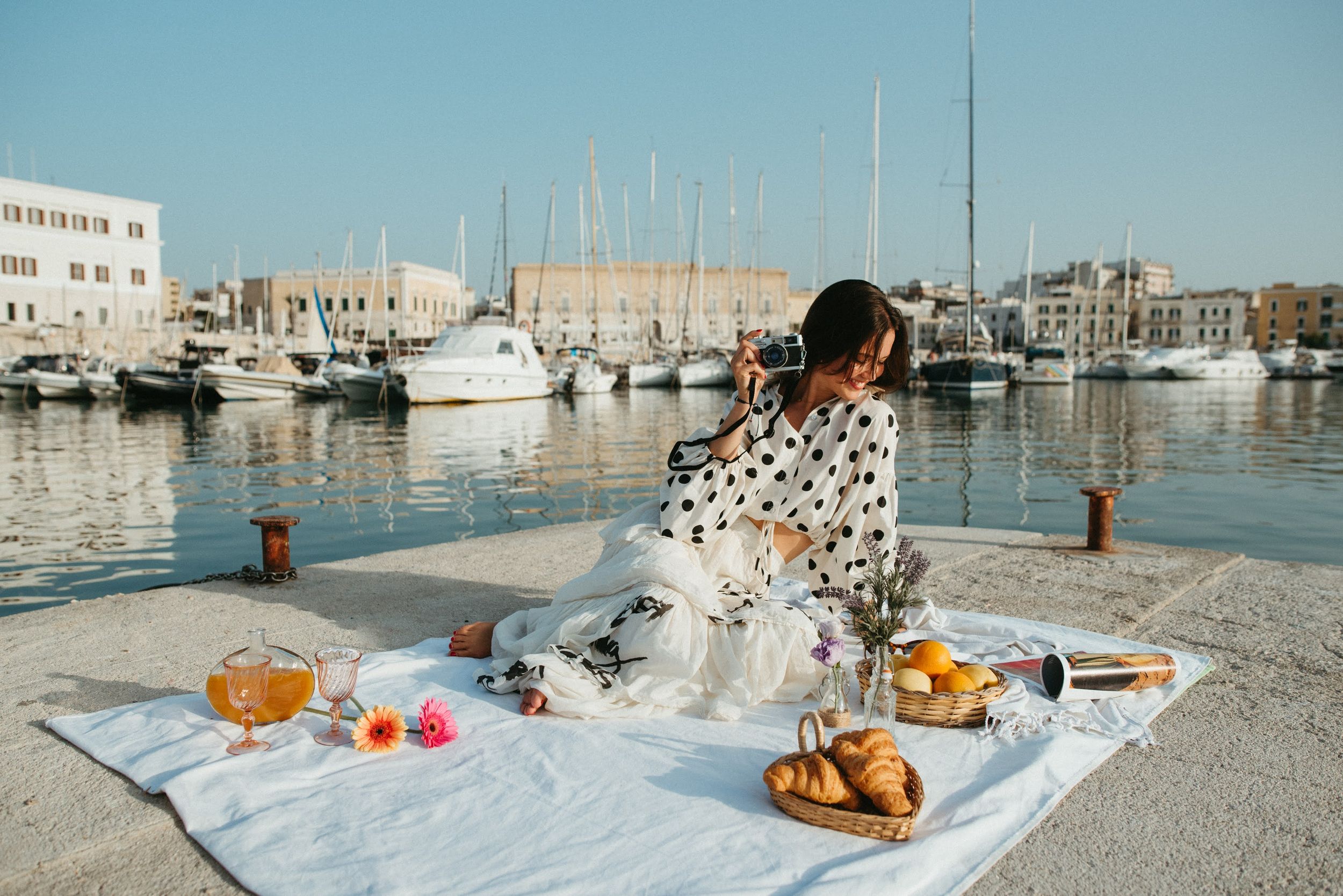 Elegant seaside picnic setup with fresh fruits and snacks along marina waterfront.