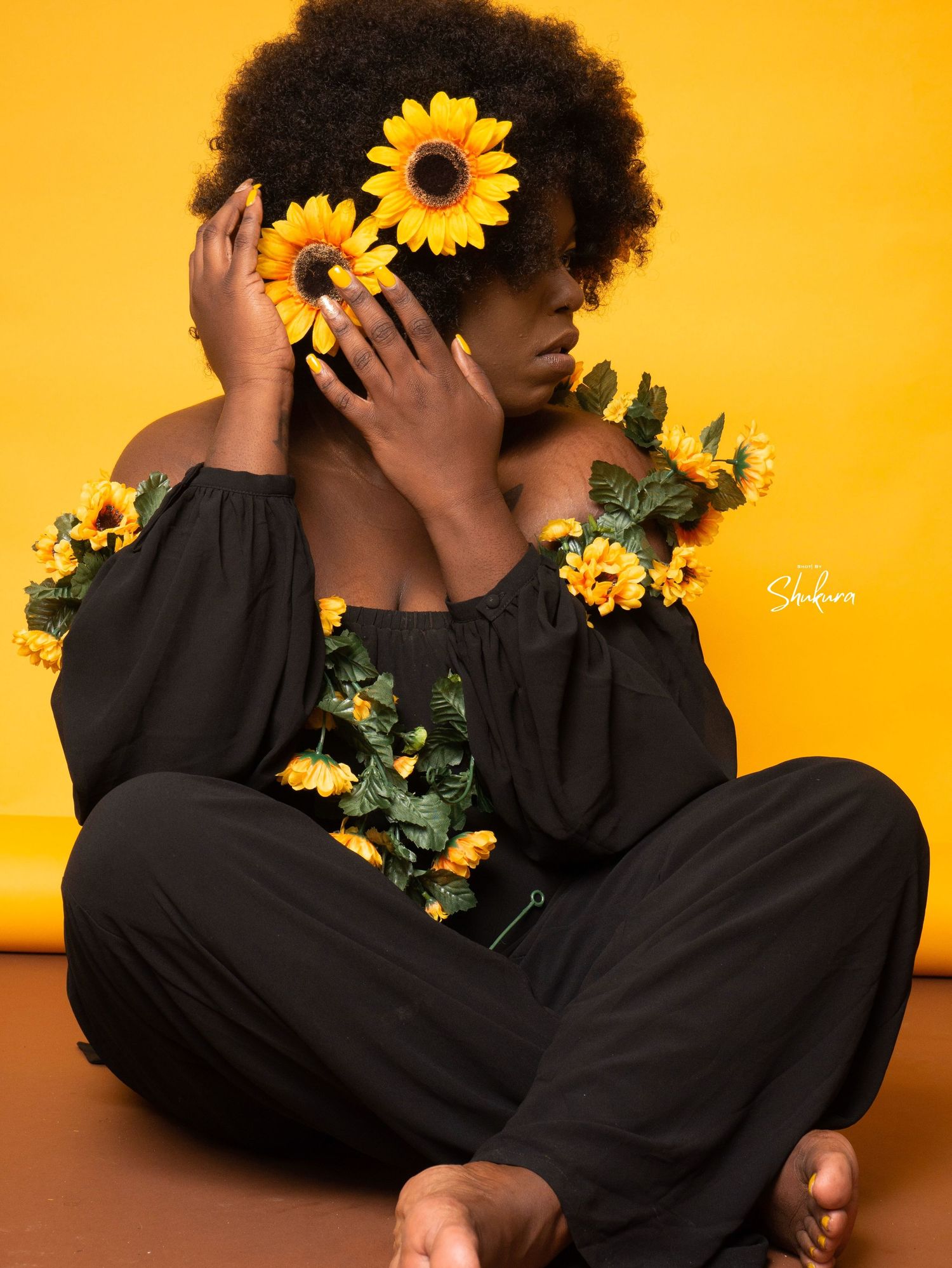 Artistic black and yellow composition with sunflowers and off-shoulder dress.