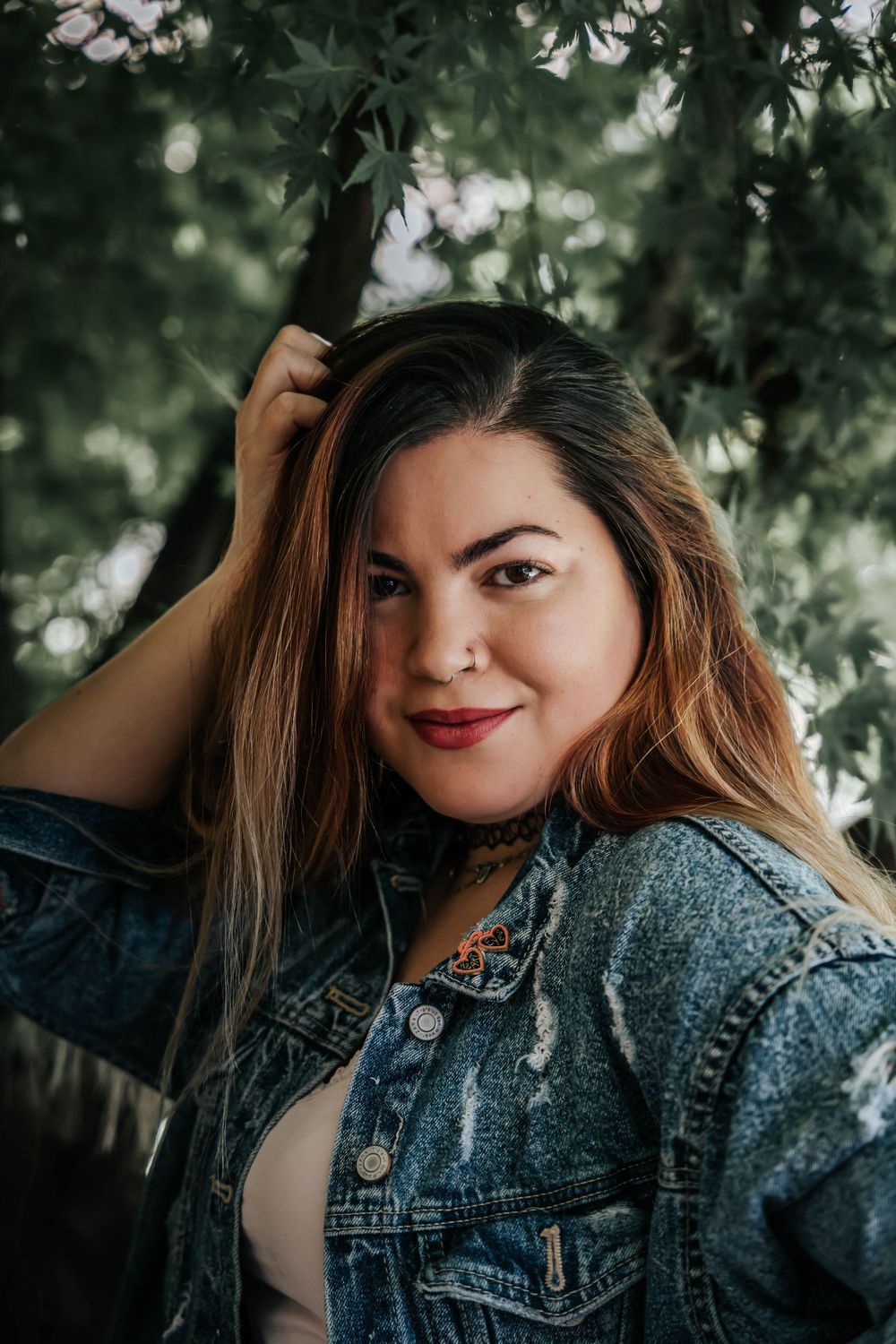 Outdoor portrait with soft natural lighting showcasing casual denim style and flowing hair.