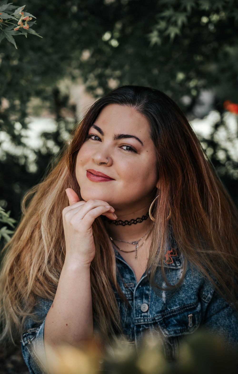 Portrait showing genuine laughter and joy while wearing a denim jacket against a natural outdoor background.