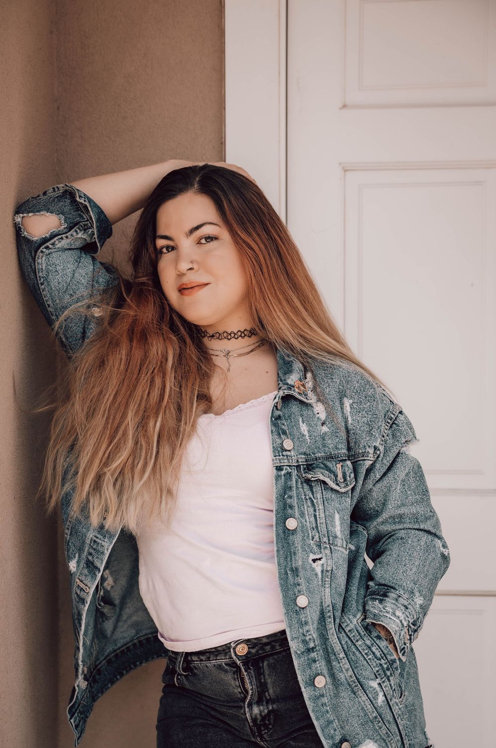 Fashion portrait series showcasing vintage denim jacket styled with pink top against white door.