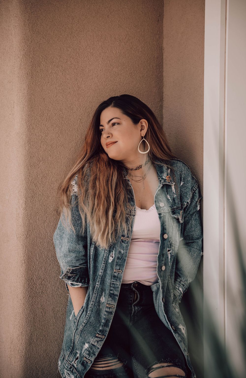 Lifestyle portraits against neutral wall showing relaxed poses in casual denim and pink top.