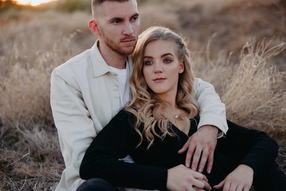 Intimate couple's portrait shot against golden dried grass background.