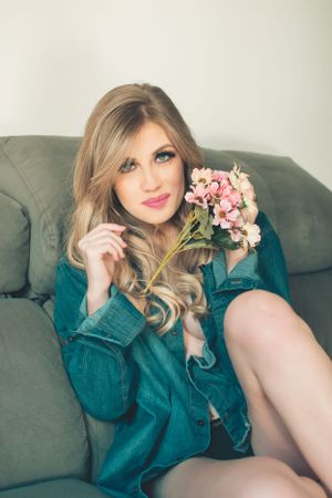 Glamour shot on grey couch with pink flowers and teal button-up dress.