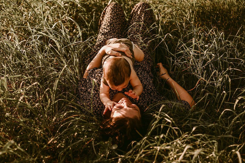 An overhead view of two people laying in tall grass during sunset.