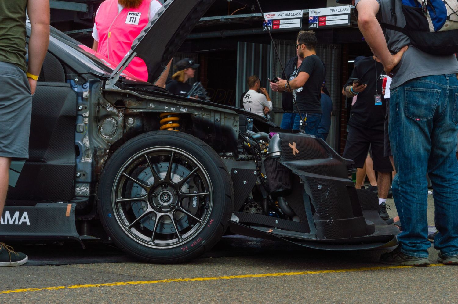 Close-up of a racing car's front wheel and suspension system during a pit stop.