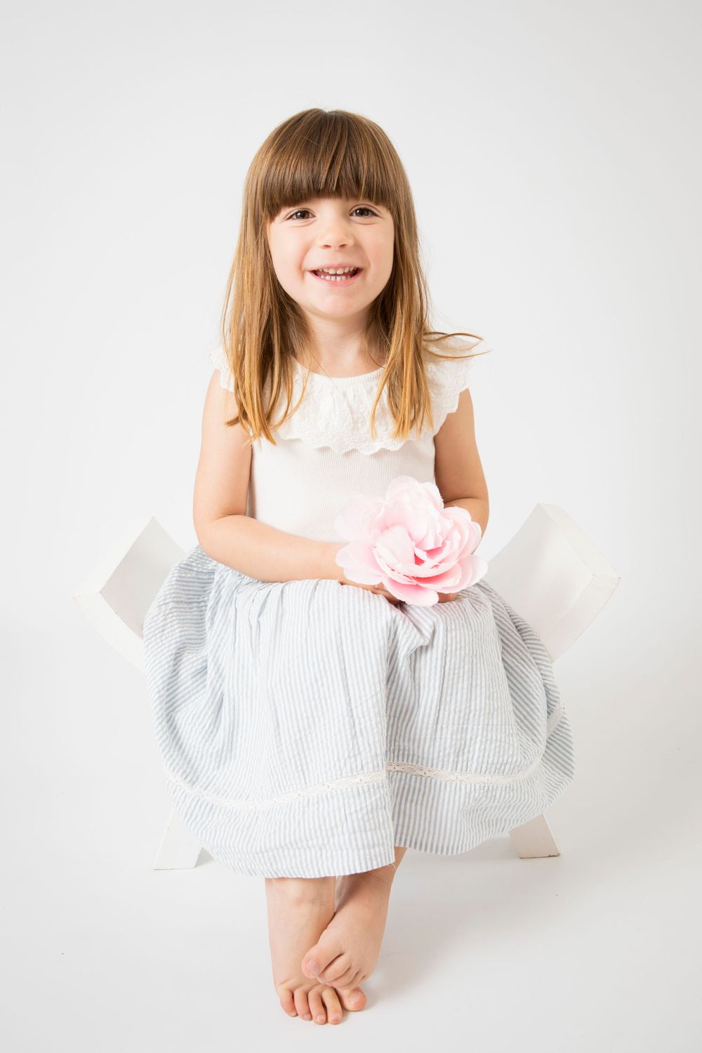 Girl holding flower, sat on white curve chair