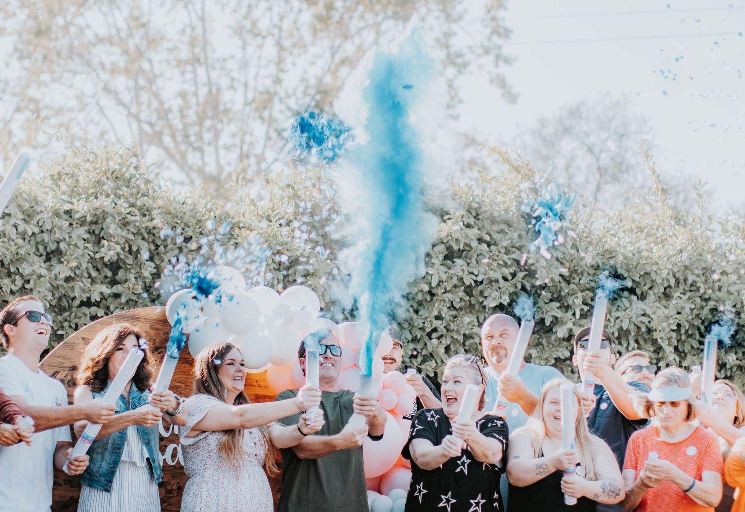 Group celebration with blue smoke bombs creating a festive outdoor atmosphere.