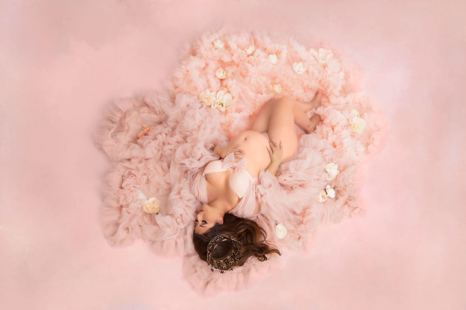 Overhead view of maternity portrait with pink tulle and floral elements.