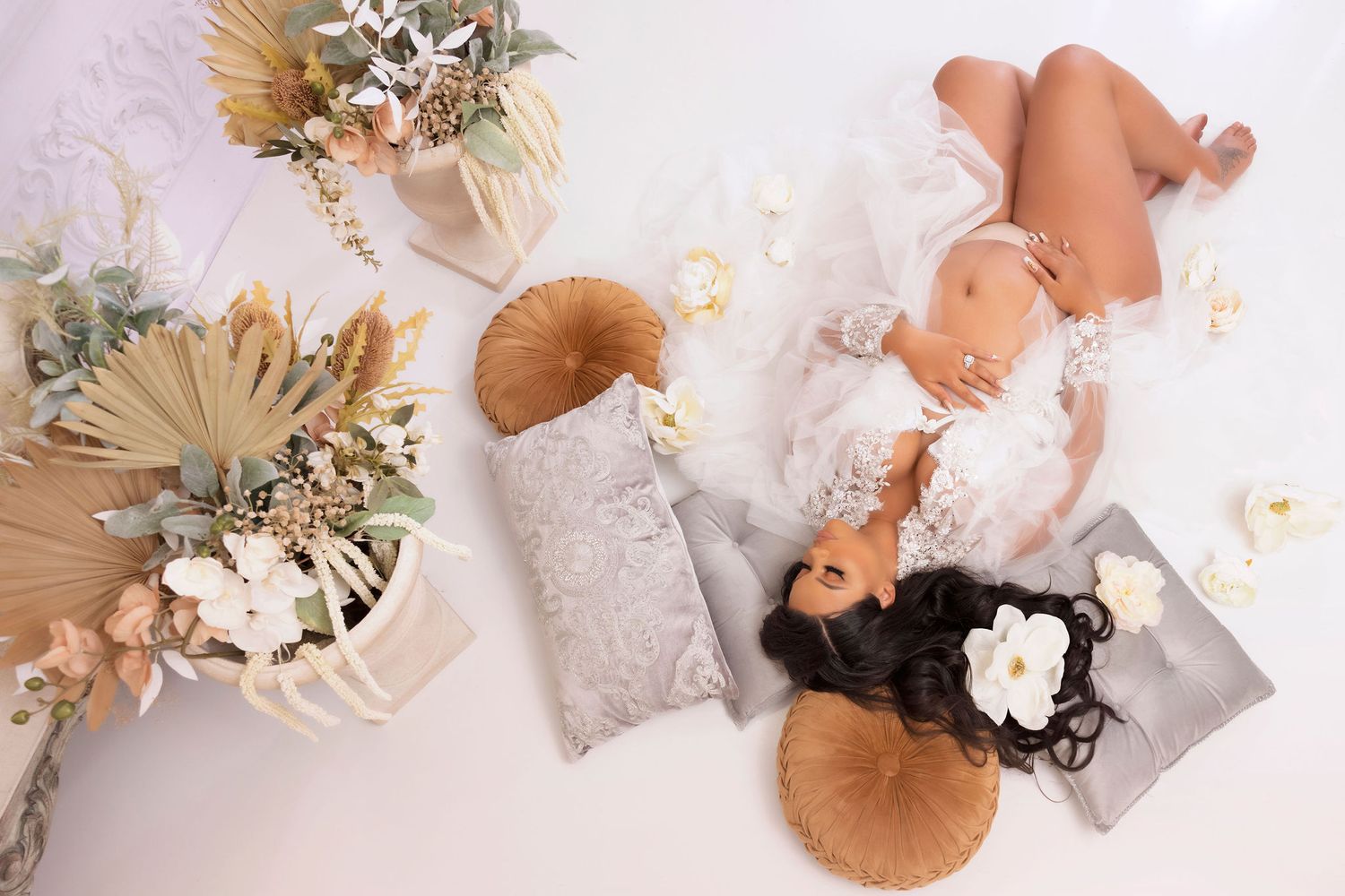 Aerial photo with dried palm leaves and floral arrangements in neutral tones on white background.