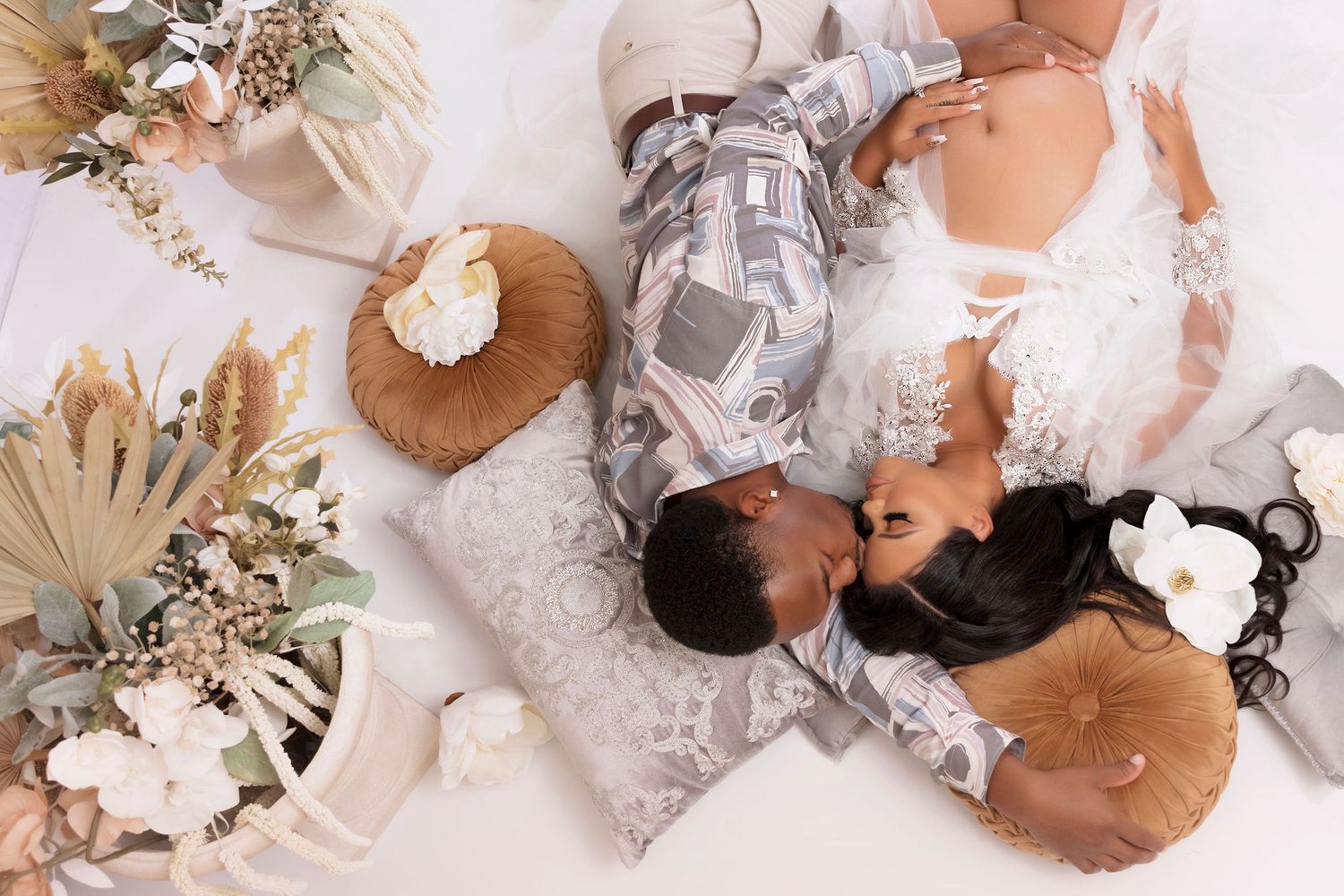 Overhead view of couple lying on floor surrounded by dried floral arrangements and neutral decor.