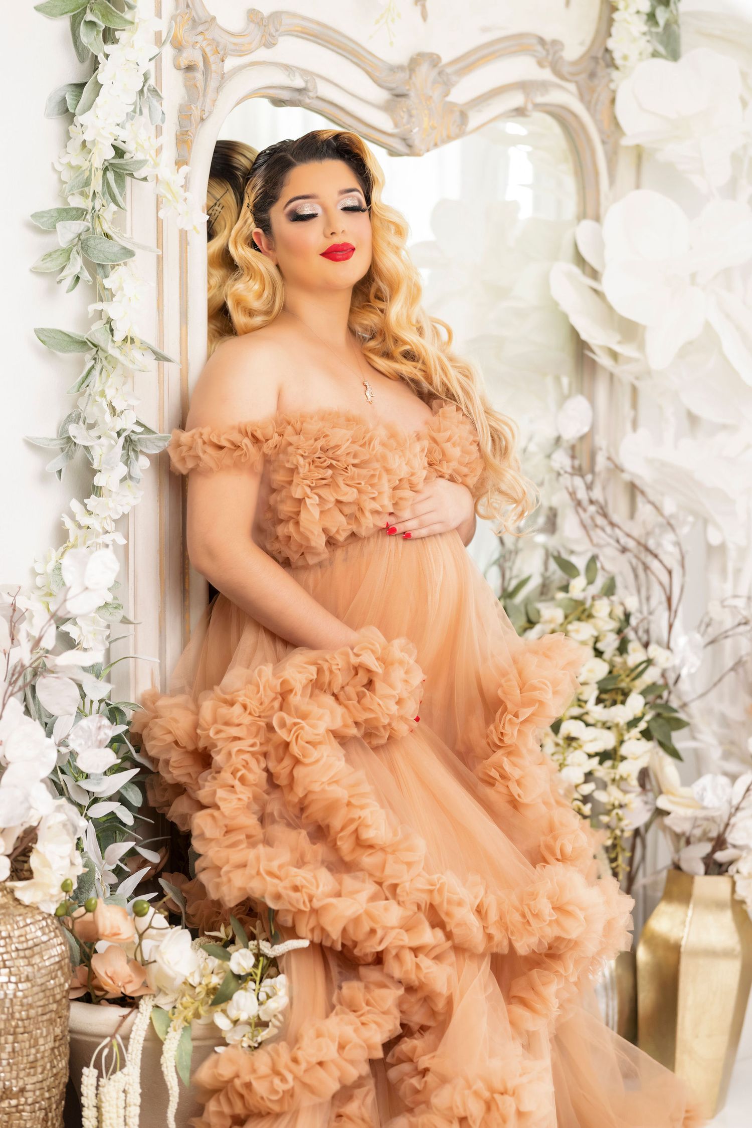Romantic maternity portrait in peach tulle gown against ornate white mirror backdrop.