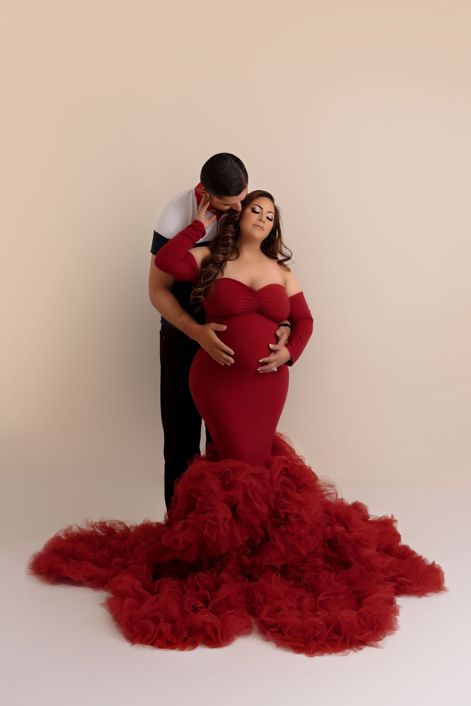 Romantic maternity portrait featuring a dramatic red mermaid gown with ruffled tulle train.