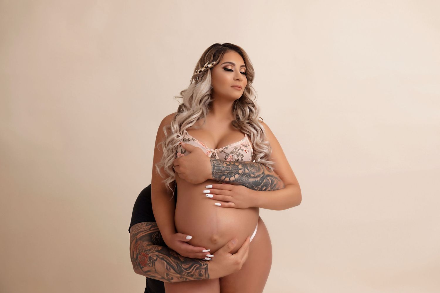 Artistic maternity portrait in intimate lingerie on beige background.