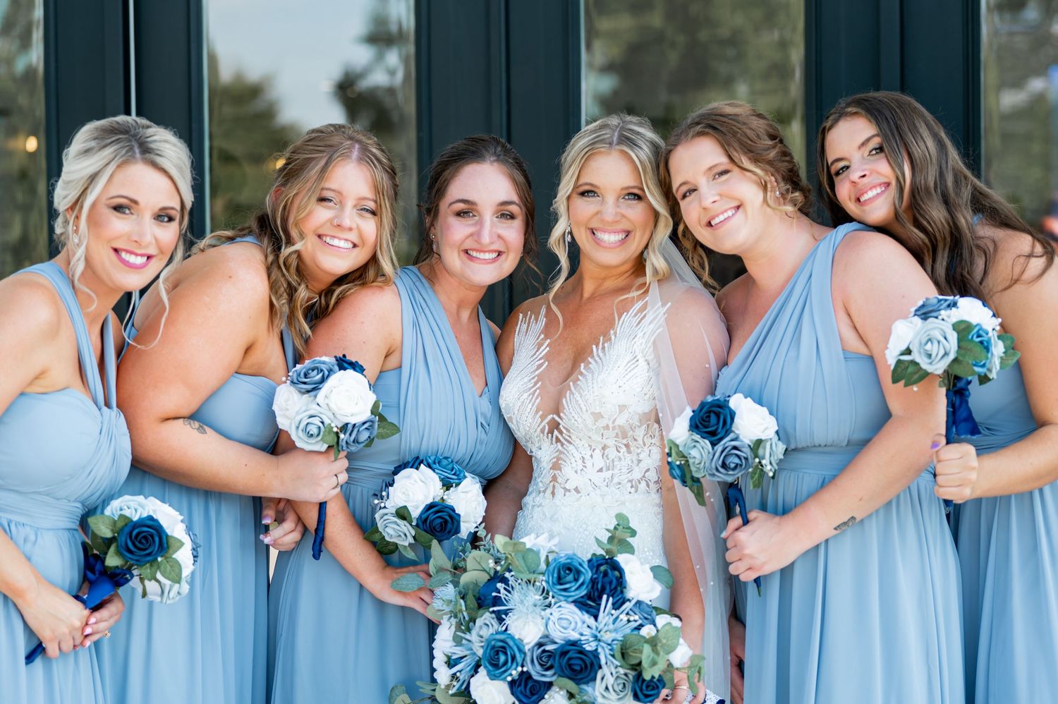 Bridesmaids in light blue dresses pose playfully for wedding photos.