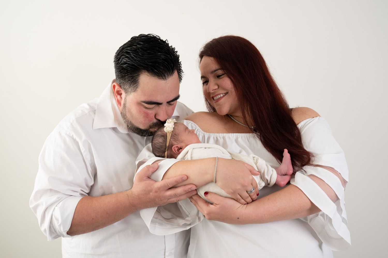 New parents lovingly gaze at their newborn baby wrapped in white blanket.