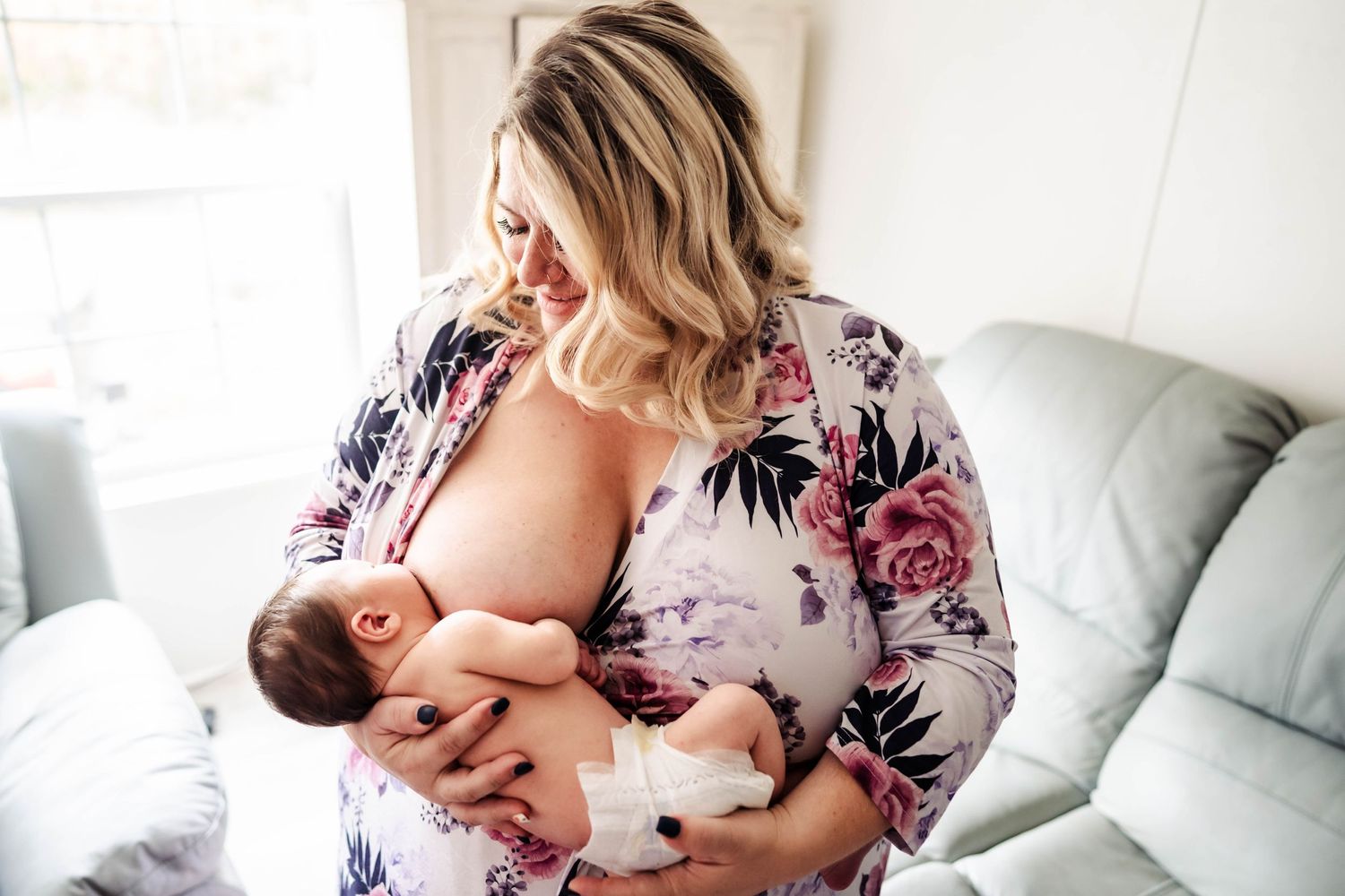 Woman looking down at her newborn baby while she breastfeeds.