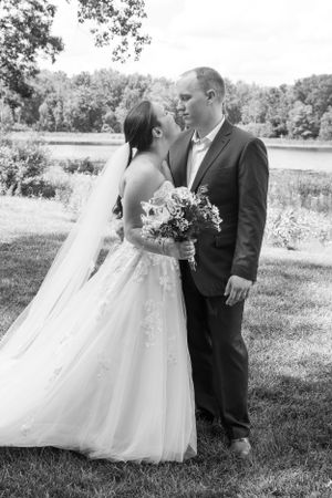 Black and white portrait of wedding couple standing together in outdoor garden setting.