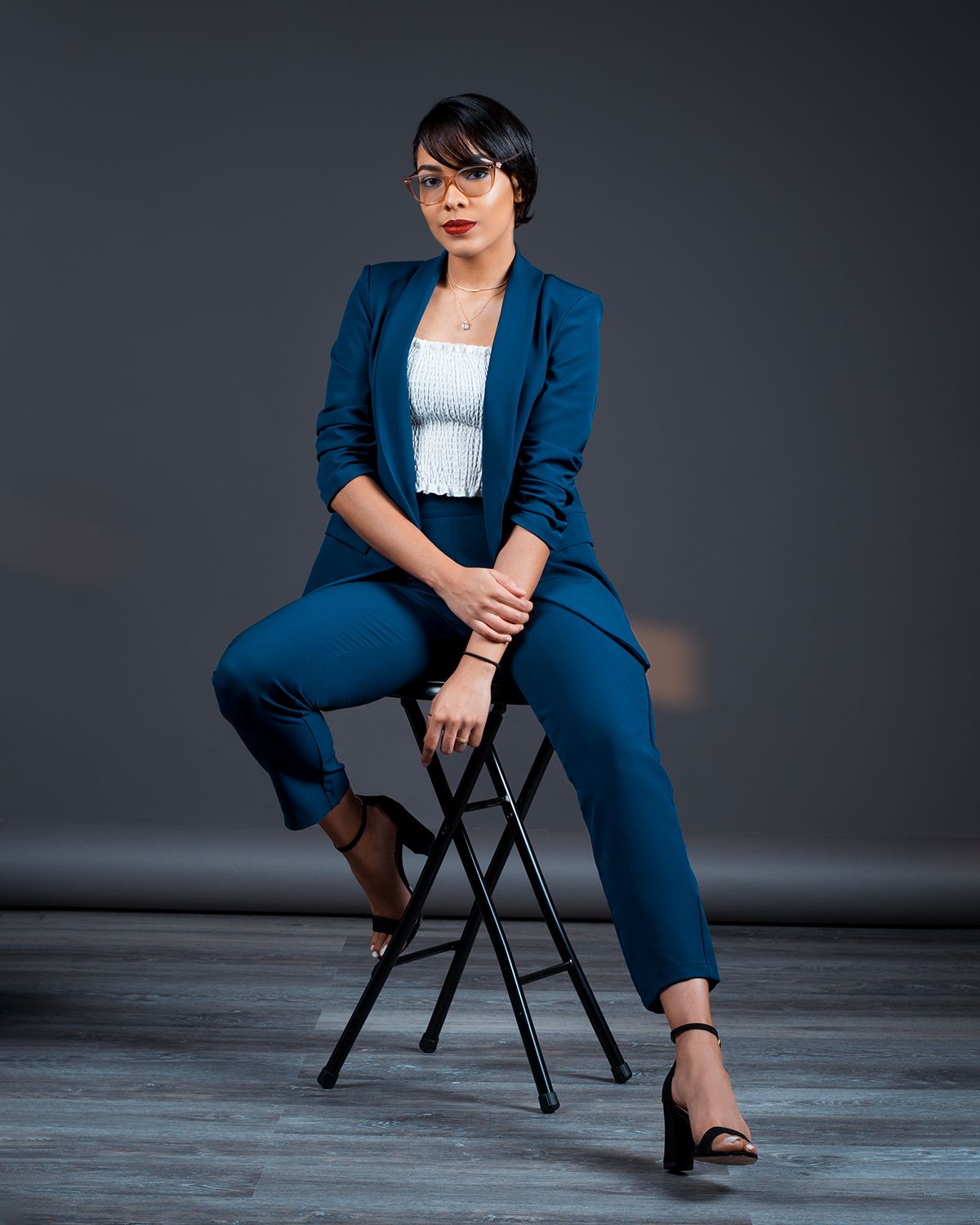 Personal branding studio photography in Allentown PA of professional woman in blue suit sitting on stool.