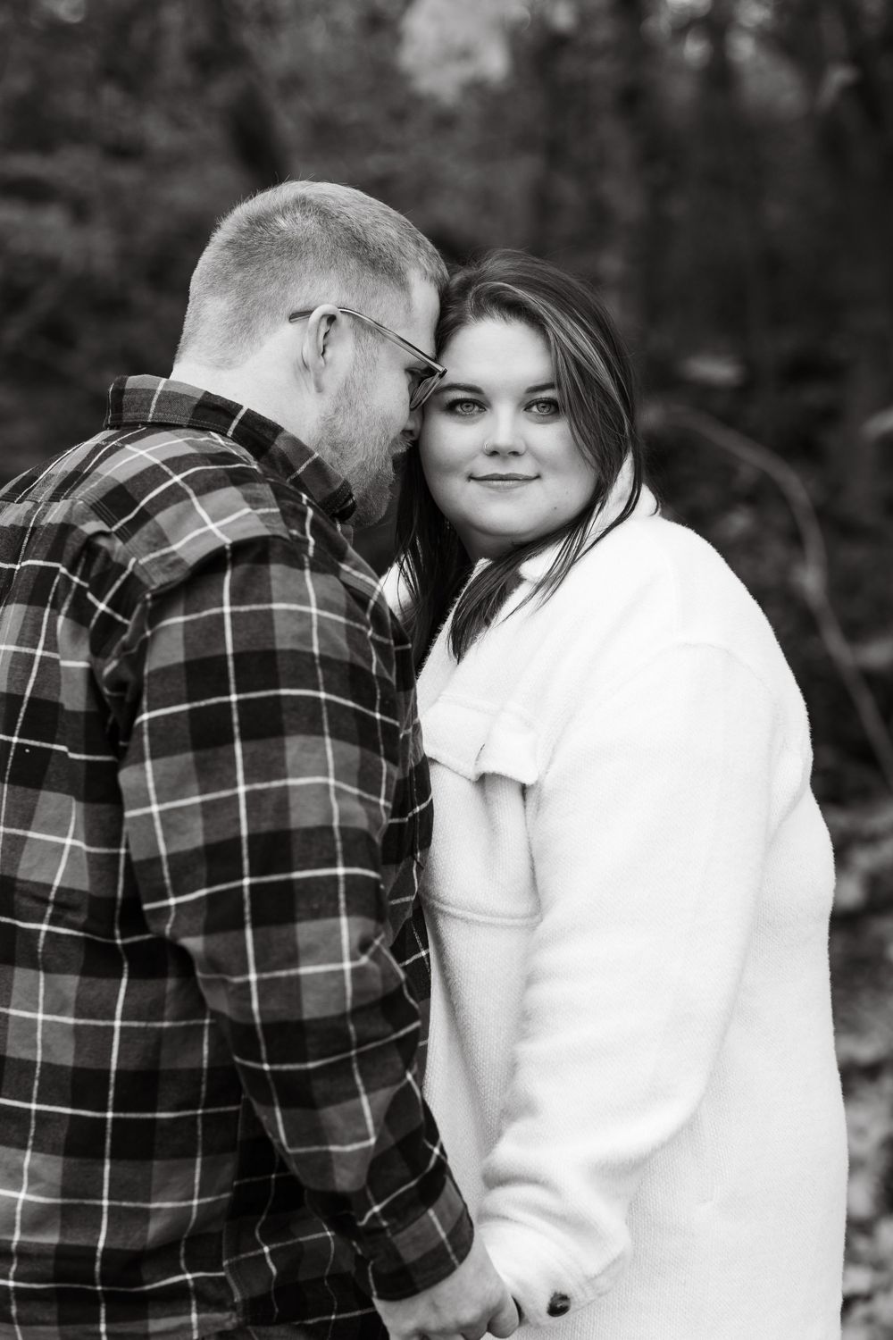 Black and white portrait of couple in casual attire sharing tender moment.