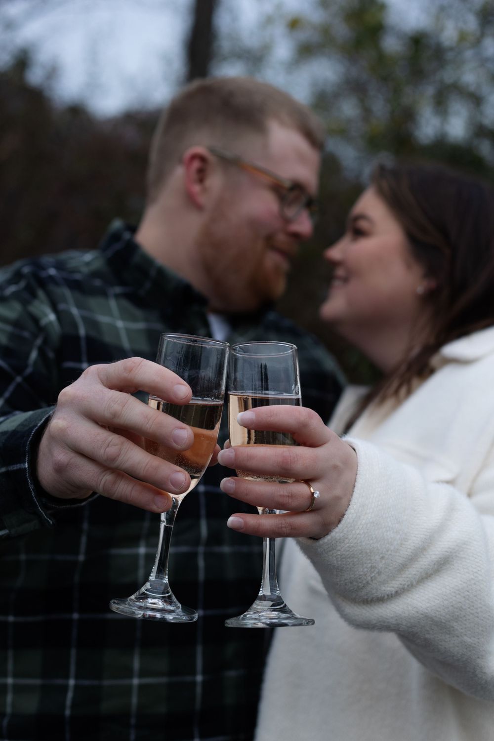 A couple toasts with champagne glasses while sharing an intimate moment outdoors.