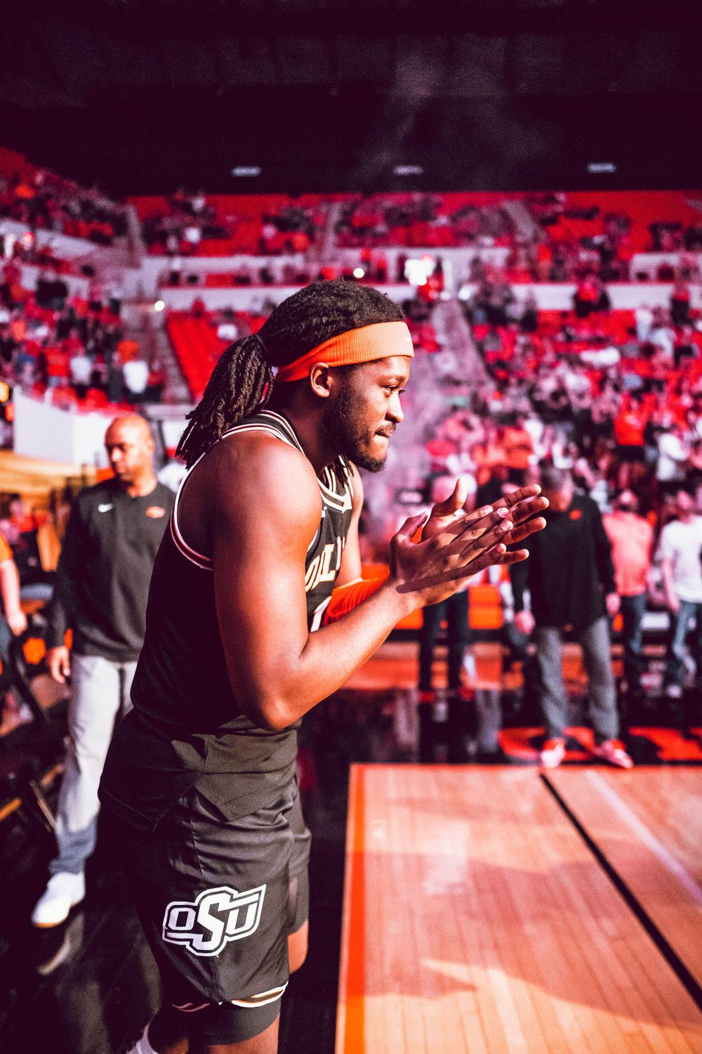 Basketball player in dark jersey gestures while standing on court during game.