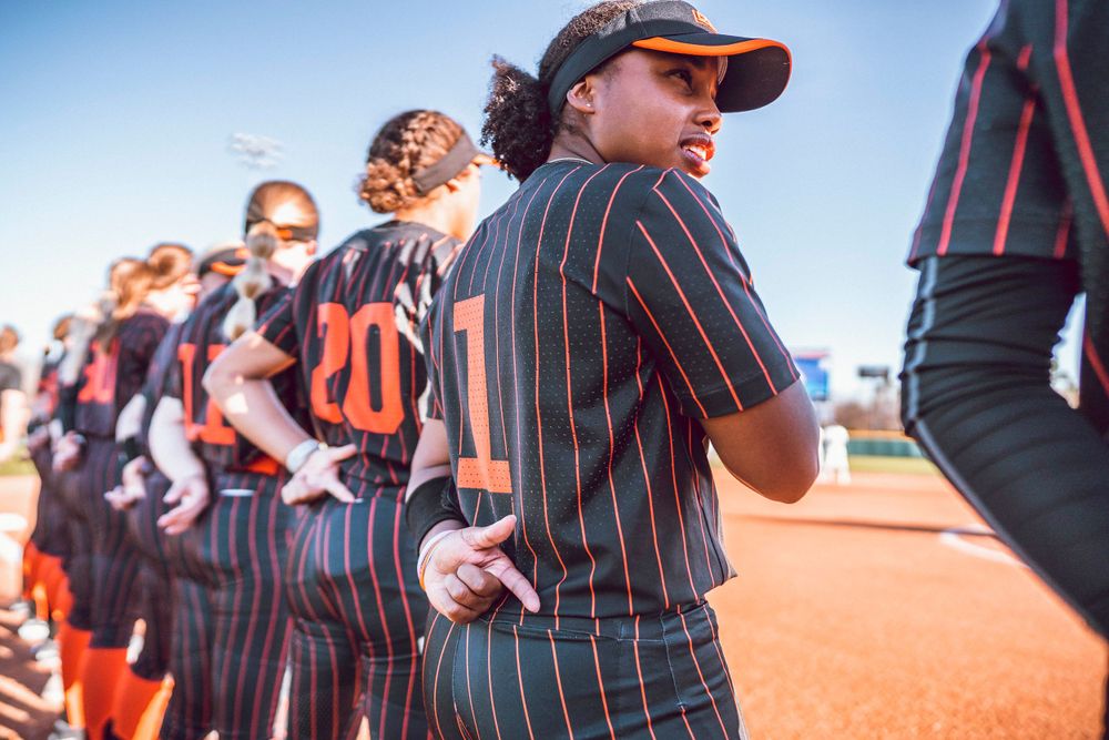 Oklahoma State softball team lines up on the field wearing pinstriped uniforms during a game.