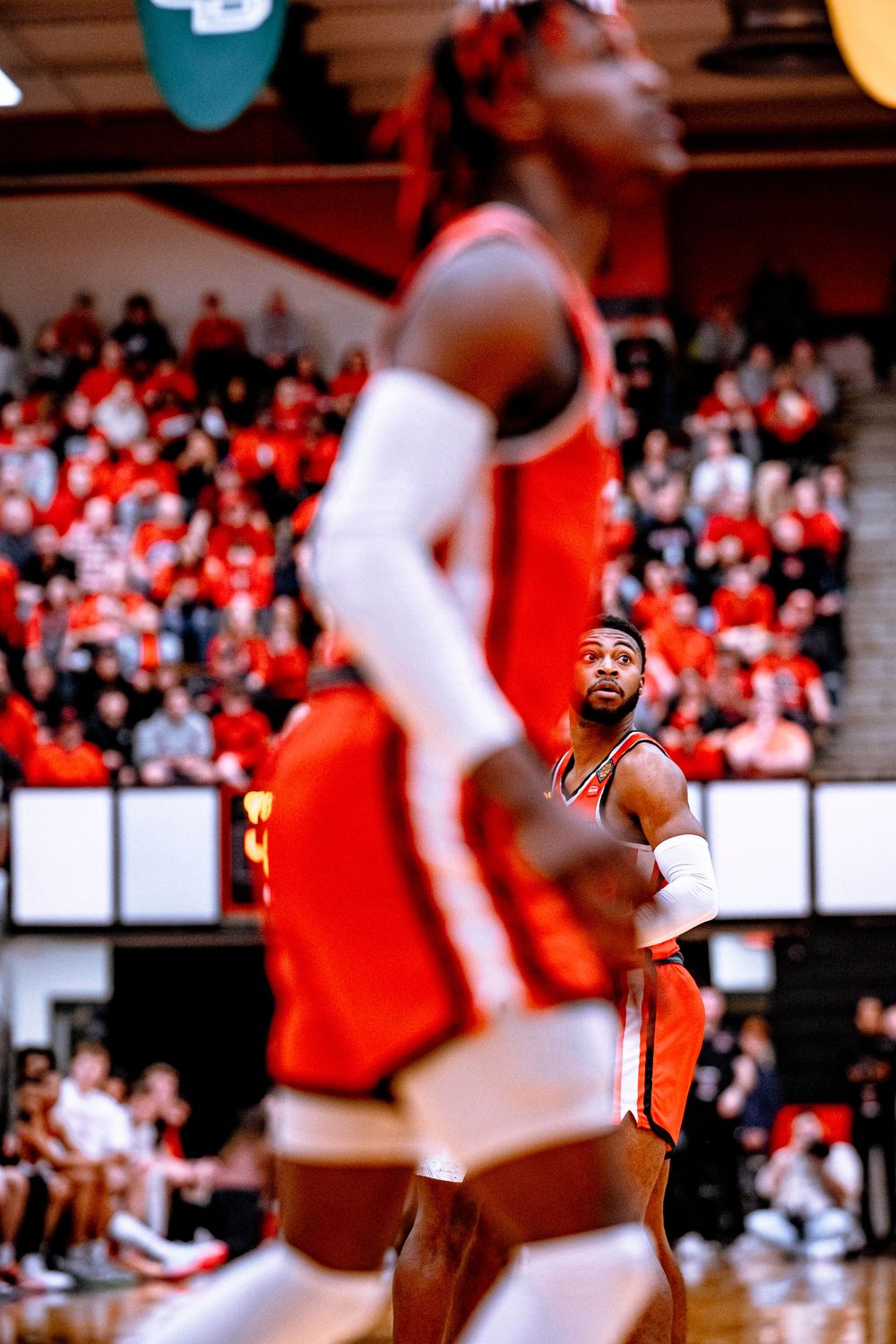 Basketball players in orange and white uniforms during an intense game moment.