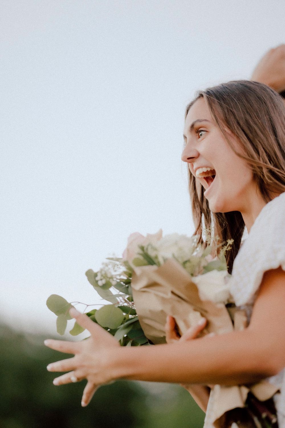 A side profile shows pure joy and excitement during an outdoor proposal moment.