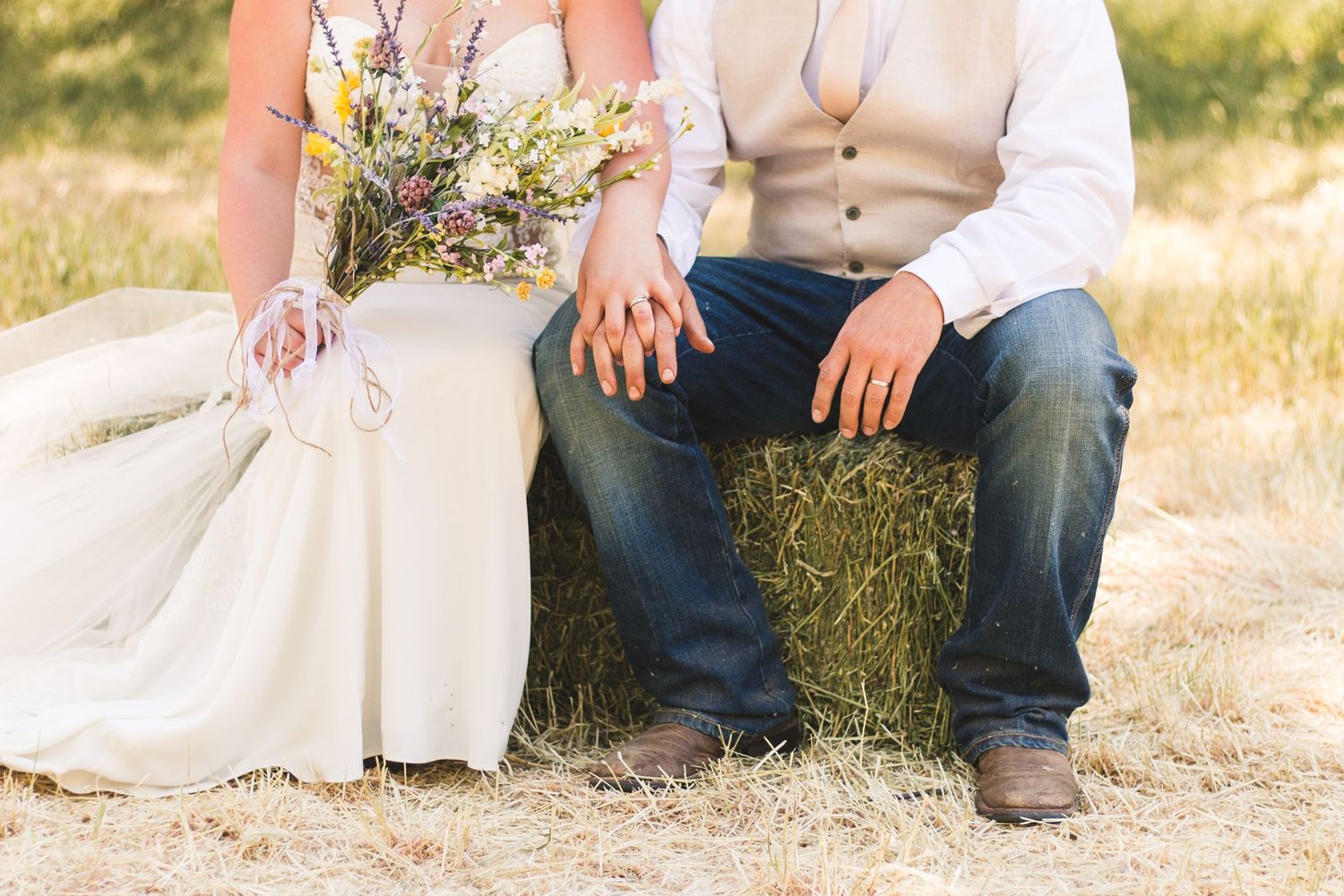 Bride and groom sitting on hay bale in Arizona