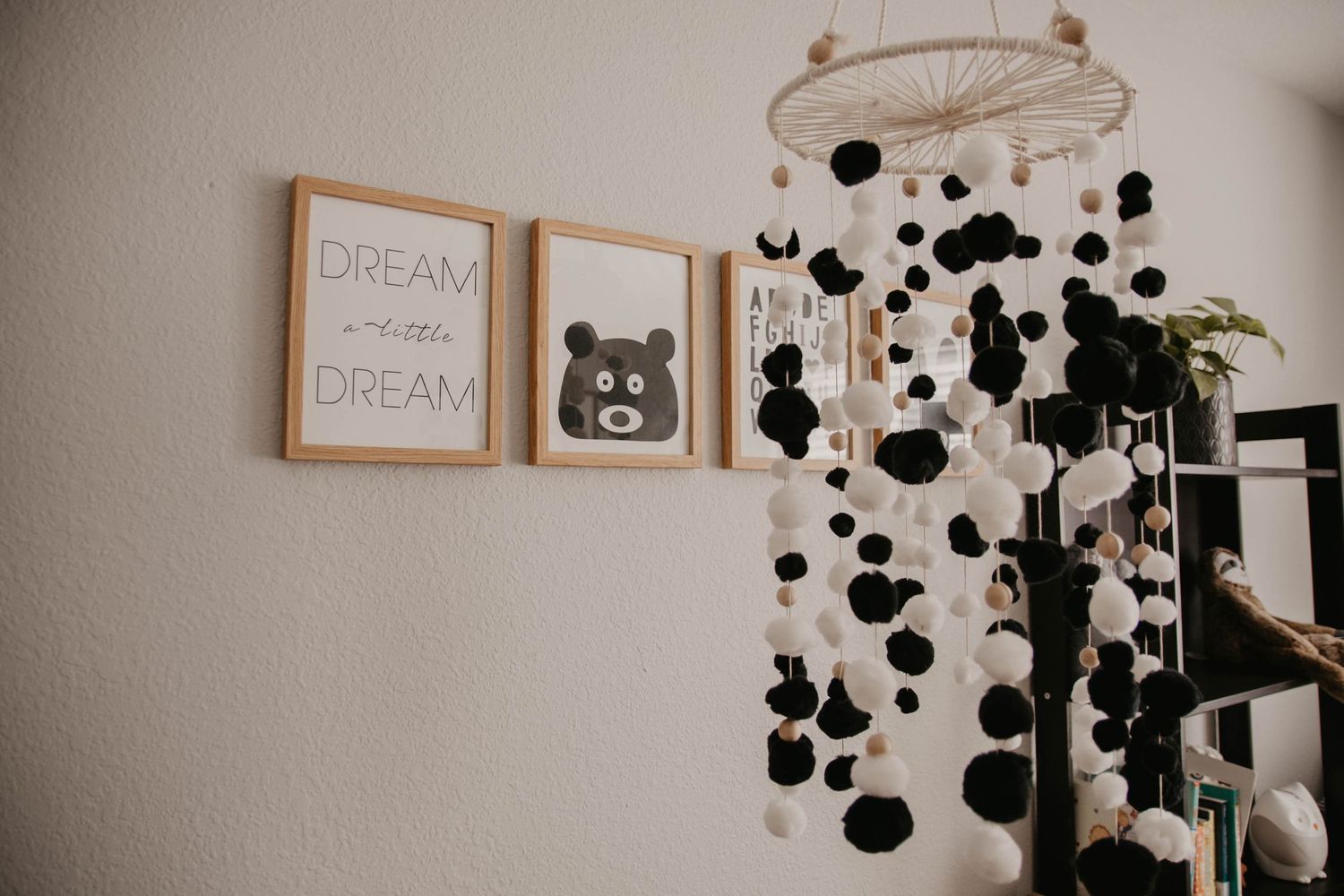 Modern nursery room with minimalist decor featuring black polka dot wall art and wooden crib.