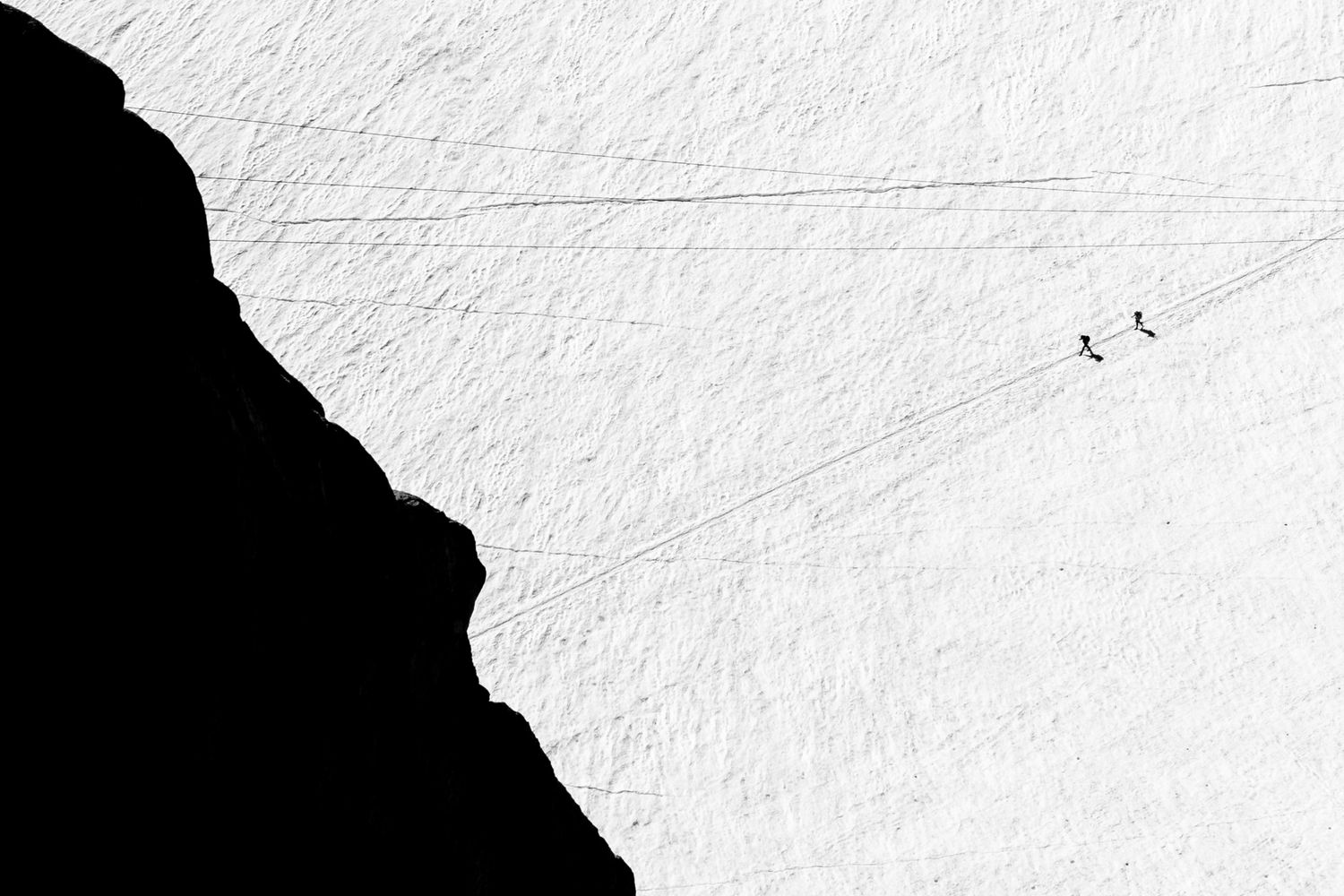 Minimalist black and white landscape with silhouetted cliff and birds in flight.