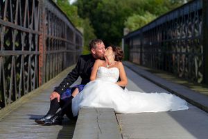 wedding couple sitting on a bridge