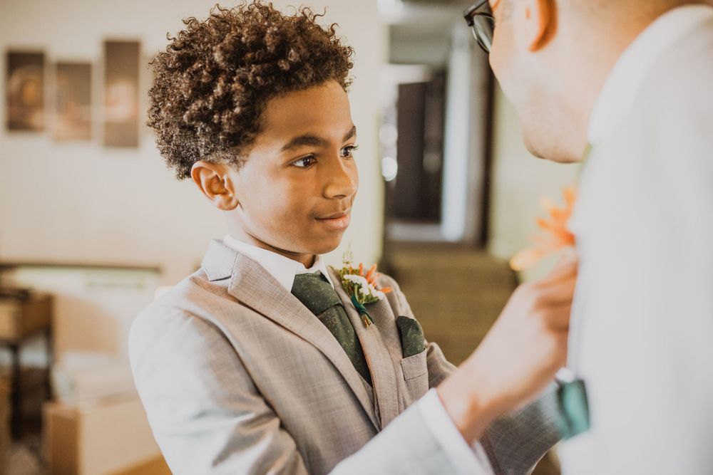 Groomsmen in light gray suits share a candid moment during wedding preparations.