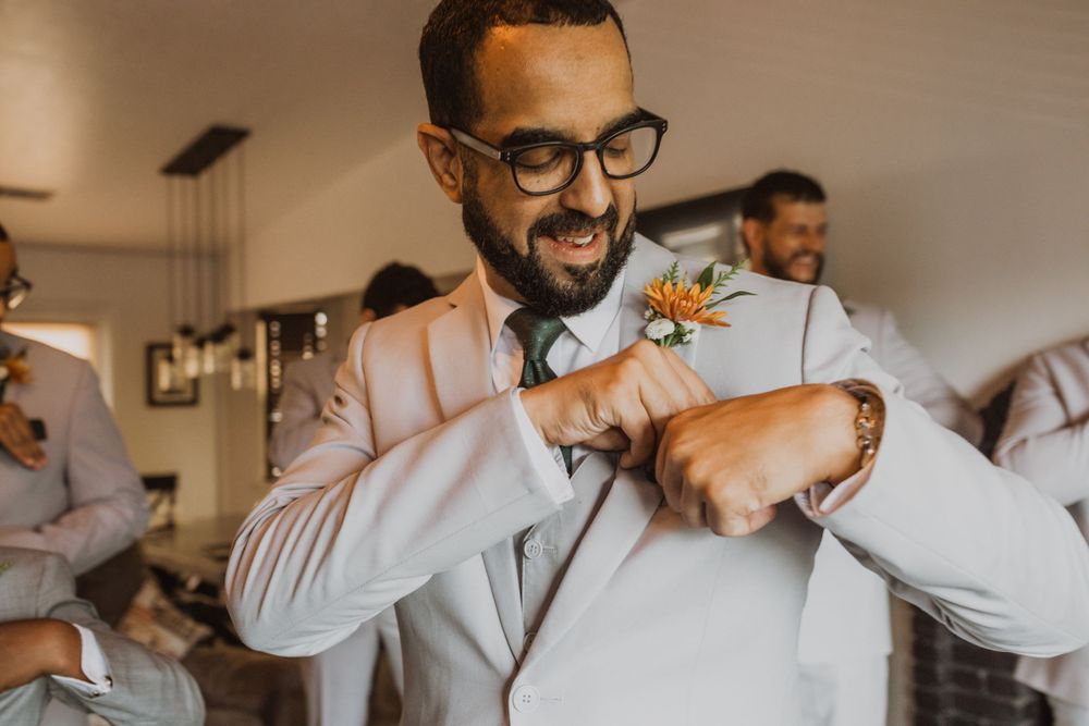 Candid moments of wedding preparation as groomsmen help with final touches.