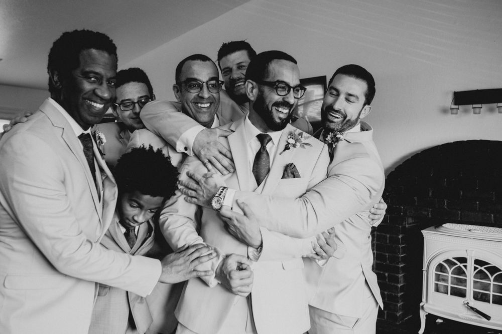 Black and white photo of groomsmen in light suits sharing joyful moments together.